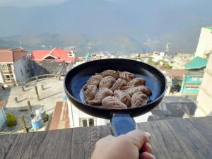 Kurseong的住宿－International Youth Hostel and Homestay Kurseong Bazar，把甜甜圈放在 ⁇ 上的人