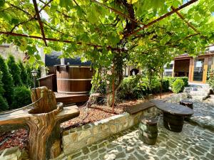 un jardín con un banco y un árbol en Къща за гости “Александър”, en Velingrad