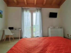 a bedroom with a red bed and a desk and a window at Corte del Sole in Valeggio sul Mincio