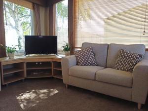 a living room with a couch and a television at 2 Bedroom Static Caravan C3 on quiet park near Talacre and Prestatyn in Prestatyn