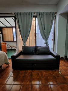 un sofá negro sentado en una sala de estar con cortinas en ocupado en Buenos Aires