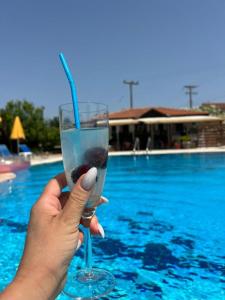 a person holding a wine glass in front of a swimming pool at Lecini Studios in Laganas