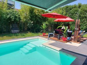 a swimming pool with a red umbrella and a chair and a table and an umbrella at Gate 25 in Blotzheim