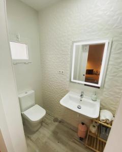 a white bathroom with a toilet and a sink at La Casita M&S in Albacete