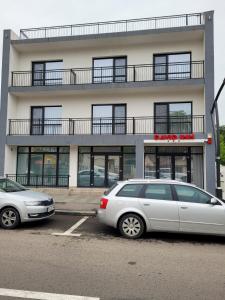 Dos coches estacionados en un estacionamiento frente a un edificio. en David INN, en Băile Felix