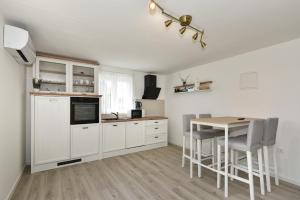 uma cozinha com armários brancos e uma mesa com cadeiras em Magda em Kožino