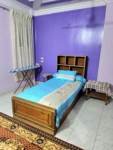 a bedroom with a bed and a purple wall at Family friendly 3 bedrooms apartment for rent in Hadayek El Maadi. in Cairo