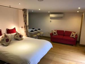 1 dormitorio con 1 cama grande y 1 sofá rojo en Fantastic Cotswolds hideaway Cleeve Hill, en Southam