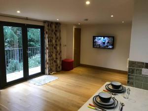 a living room with a kitchen with a table and a television at Fantastic Cotswolds hideaway Cleeve Hill in Southam