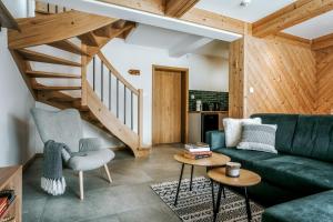 a living room with a green couch and wooden stairs at Apartamenty Krokus przy Polanie Biały Potok in Witów +32 photos