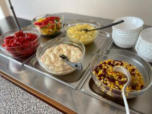 a counter top with bowls of different types of food at Hotel Koralpe in Elsenbrunn
