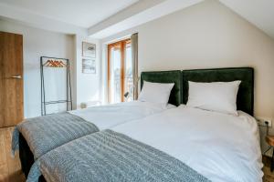 a bedroom with two white beds with a green headboard at Apartamenty Krokus przy Polanie Biały Potok in Witów