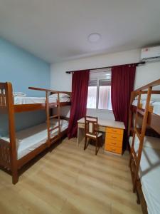 a room with three bunk beds and a desk and a table at Top view hostel in Durrës