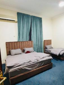a bedroom with two beds with blue curtains at Bedya Farm in Khor Fakkan