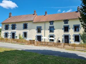 un grand bâtiment blanc avec une clôture en bois dans l'établissement Meadow View Gîtes - Grande gîtes, piscine, wi-fi - Janaillat, Creuse, France, 23250, à Janaillat