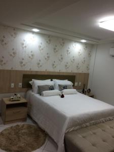 a bedroom with a large bed with white sheets and floral wallpaper at Hotel Arezzu in Linhares