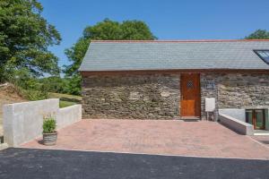 a stone building with a wooden door and a patio at Owls Roost 2 en-suites, nr Port Isaac & Tintagel in Camelford