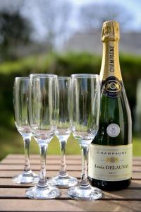 four wine glasses and a bottle of champagne on a table at Owls Roost 2 en-suites, nr Port Isaac & Tintagel in Camelford