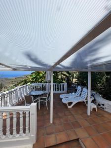 un patio con sombrilla blanca, sillas y el océano en Casa Buena Vista, en Jedey