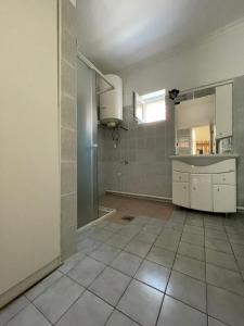 a kitchen with white cabinets and a tile floor at Zsigmond Vendeghaz in Keszthely