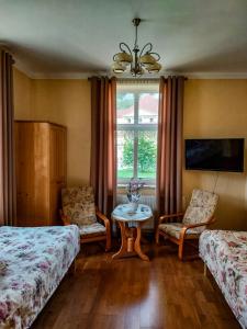 een slaapkamer met 2 bedden, een tafel en een raam bij Apartament Pułaskiego in Krynica Zdrój