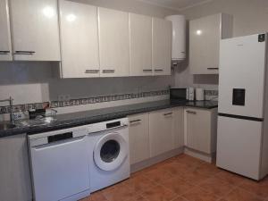 a kitchen with a washing machine and a refrigerator at The Beach Hut with Lazy spa in Adra