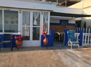 une maison bleue et blanche avec un vase de fleurs sur une terrasse couverte dans l'établissement The Beach Hut with Lazy spa, à Adra