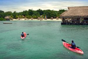 two people in kayaks in the water near a beach at Bluewater Maribago Beach Resort in Mactan