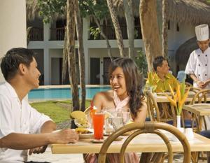 a man and woman sitting at a table in a restaurant at Bluewater Maribago Beach Resort in Mactan
