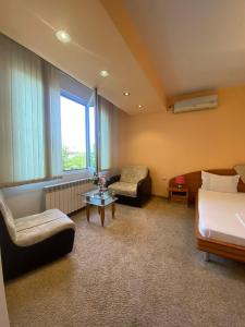 ein Hotelzimmer mit einem Bett, einem Sofa und einem Stuhl in der Unterkunft hotel TEDI in Assenowgrad