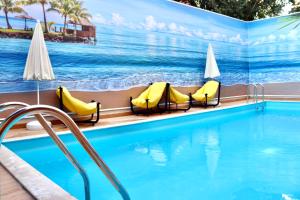 a swimming pool with yellow chairs and a painting of the ocean at Old Town Point Hotel & Spa Antalya in Antalya