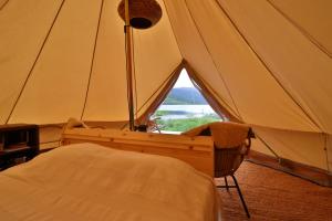 a bedroom with a tent with a bed and a window at Fossumsanden Camping og Hytter in Fyresdal