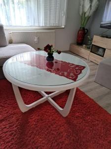 a white coffee table with a glass top on a red rug at Kuća za odmor KOD MARE in Vukovar