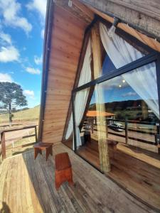 a large window on the deck of a log cabin at Chalé A-Frame da Fazenda in Bom Jardim da Serra