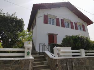 een wit huis met rode luiken en trappen bij Chambres d'hôtes "HOR DAGO" près de la gare d'Hendaye avec le petit-déjeuner in Hendaye