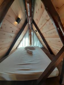 a bed in a wooden cabin with a roof at Chalé A-Frame da Fazenda in Bom Jardim da Serra