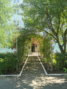 a pathway leading to a building with an arch with flowers at Apartament Ramona in Zărneşti