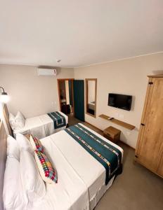 a hotel room with two beds and a flat screen tv at Quinta Santa Bárbara Pirenópolis in Pirenópolis