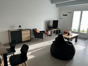een woonkamer met een zwart voorwerp op de vloer bij Location du Klan des K : villa 4 étoiles 150m plage in Les Sables Vignier