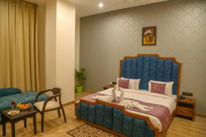 a bedroom with a large blue bed and a chair at Four Leaf Hotel, Kasganj in Kāsganj +24 photos