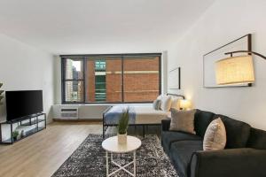 Comfortable & Convenient Studio Apt in Chicago - Chestnut 23D في شيكاغو: غرفة معيشة مع أريكة وسرير