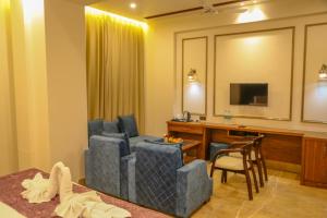a hotel room with a desk and chairs and a television at Four Leaf Hotel, Kasganj in Kāsganj