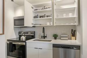 La cuisine est équipée de placards blancs, d'un évier et d'une cuisinière. dans l'établissement Comfortable & Convenient Studio Apartment- Chestnut 23D, à Chicago