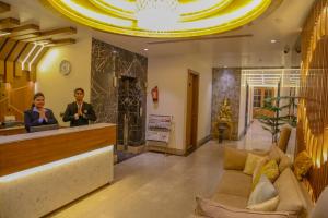 two people standing at a counter in a lobby at Four Leaf Hotel, Kasganj in Kāsganj