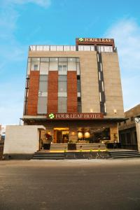 a fourleaf heart hospital building with benches in front of it at Four Leaf Hotel, Kasganj in Kāsganj