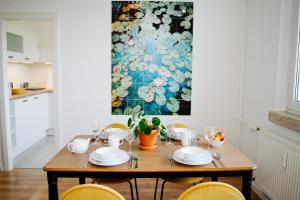 a dining room table with chairs and a painting at Jenapartments Zuhause auf Zeit, Uniklinik & Natur vor der Tür in Jena