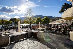 un patio con tavoli, ombrelloni e persone sedute ai tavoli di Osteria Ascona ad Ascona