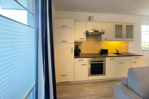 a kitchen with white cabinets and a stove top oven at MeinStrandNest in Juliusruh