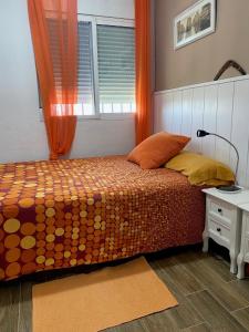 エル・プイグにあるApt. New Holiday Valencia Beachのベッドルーム1室(オレンジ色のカーテンと窓付きのベッド1台付)