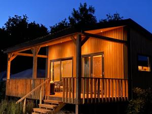 a small cabin with a porch and a deck at Camping Kleine Belterwijde, Wiede Lodge met uitzicht over het water in Belt-Schutsloot +14 photos